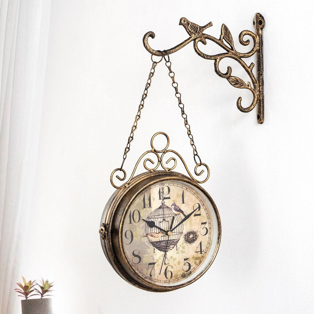 Harmore elegante wandklok met vintage uitstraling, hangend aan een decoratieve metalen muurbeugel met sierlijke vogel- en bladdetails. De klok heeft een klassiek design met een klokplaat voorzien van een vogelkooi en vogelmotief. Ideaal als stijlvolle toevoeging aan woonkamers, hallen of cafés voor een romantisch en nostalgisch accent.