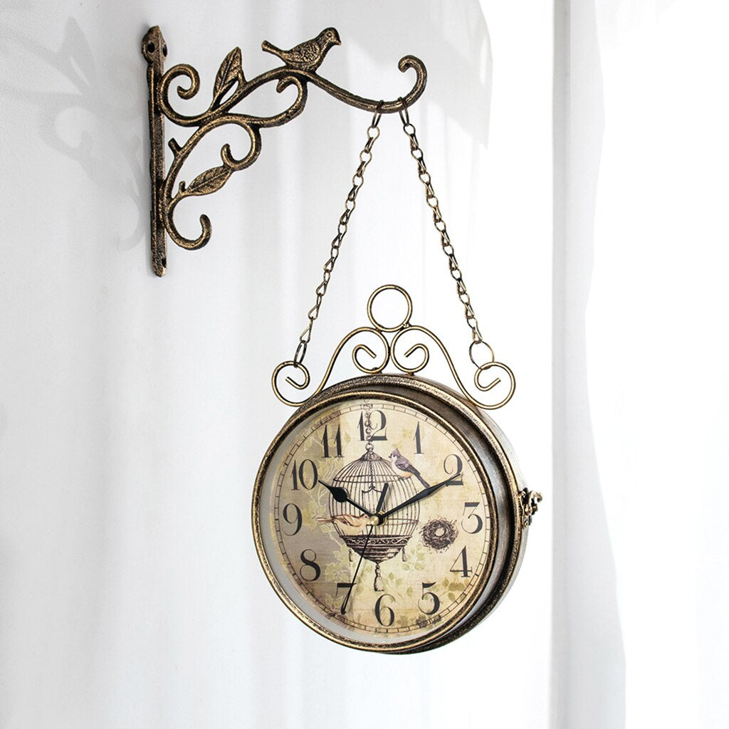 Harmore elegante wandklok met vintage design, hangend aan een metalen muurbeugel met decoratieve vogel- en bladdetails. De klok heeft een klassieke uitstraling met een klokplaat met vogelmotief en antieke wijzers. Perfect voor een nostalgisch of romantisch interieur. Geschikt voor woonkamers, hallen of cafés.