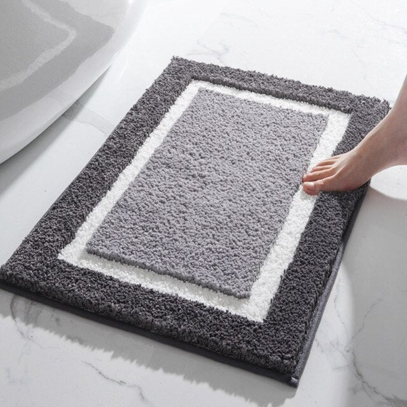 Havonia badkamer mat met een stijlvol rechthoekig design in grijs- en wittinten. De mat ligt op een marmeren vloer en een voet raakt zachtjes de rand, wat de zachte en comfortabele textuur benadrukt. Perfect om warmte en luxe toe te voegen aan de badkamer.