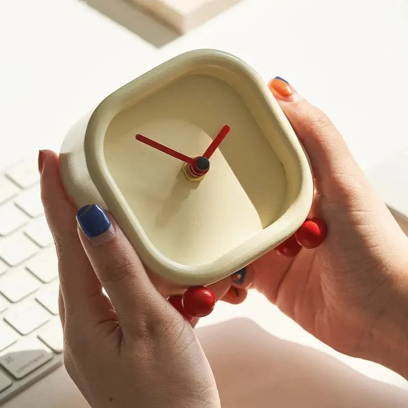 Hawley alarmklok met strak, minimalistisch ontwerp, vastgehouden in handen. De vierkante vorm en rode wijzers geven een moderne uitstraling. Perfect voor op je bureau of nachtkastje, met betrouwbare prestaties voor dagelijks gebruik.