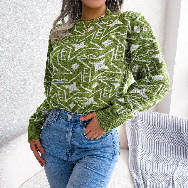 Vrouw draagt de Heskari moderne trui in groen met een opvallend geometrisch patroon in wit. De trui heeft een comfortabele pasvorm en wordt gecombineerd met een lichtblauwe jeans voor een frisse, trendy look. Ideaal voor casual dagelijkse outfits met een modieuze flair.