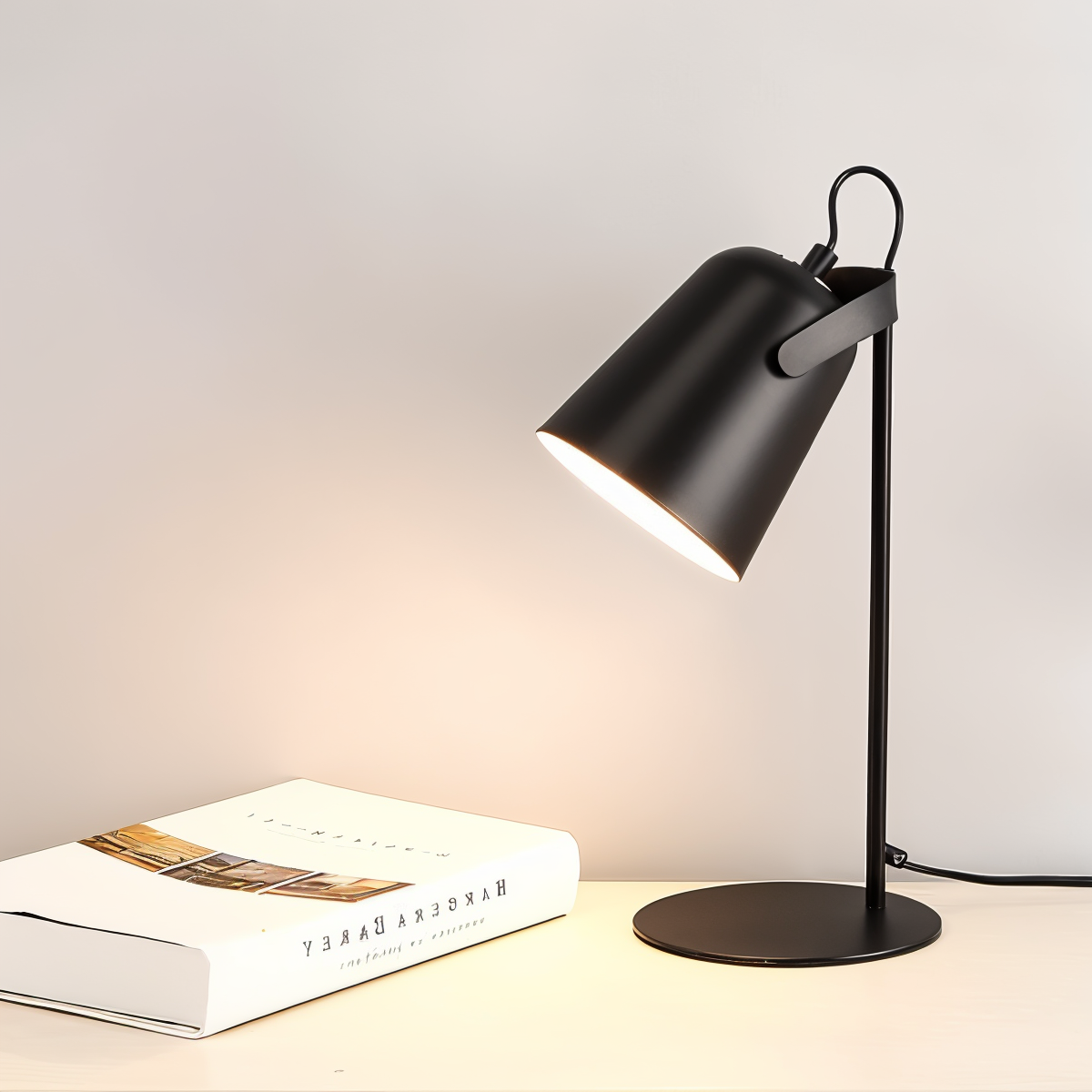JAVERTA verstelbare lamp met een strakke zwarte lampenkap en een boekenstapel op de tafel ernaast