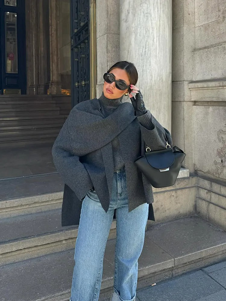 Moderne, tijdloze Kallista jas in donkergrijs, gedragen met een chique tas en accessoires voor een verfijnde uitstraling. Perfect voor een elegante casual look in de stad.