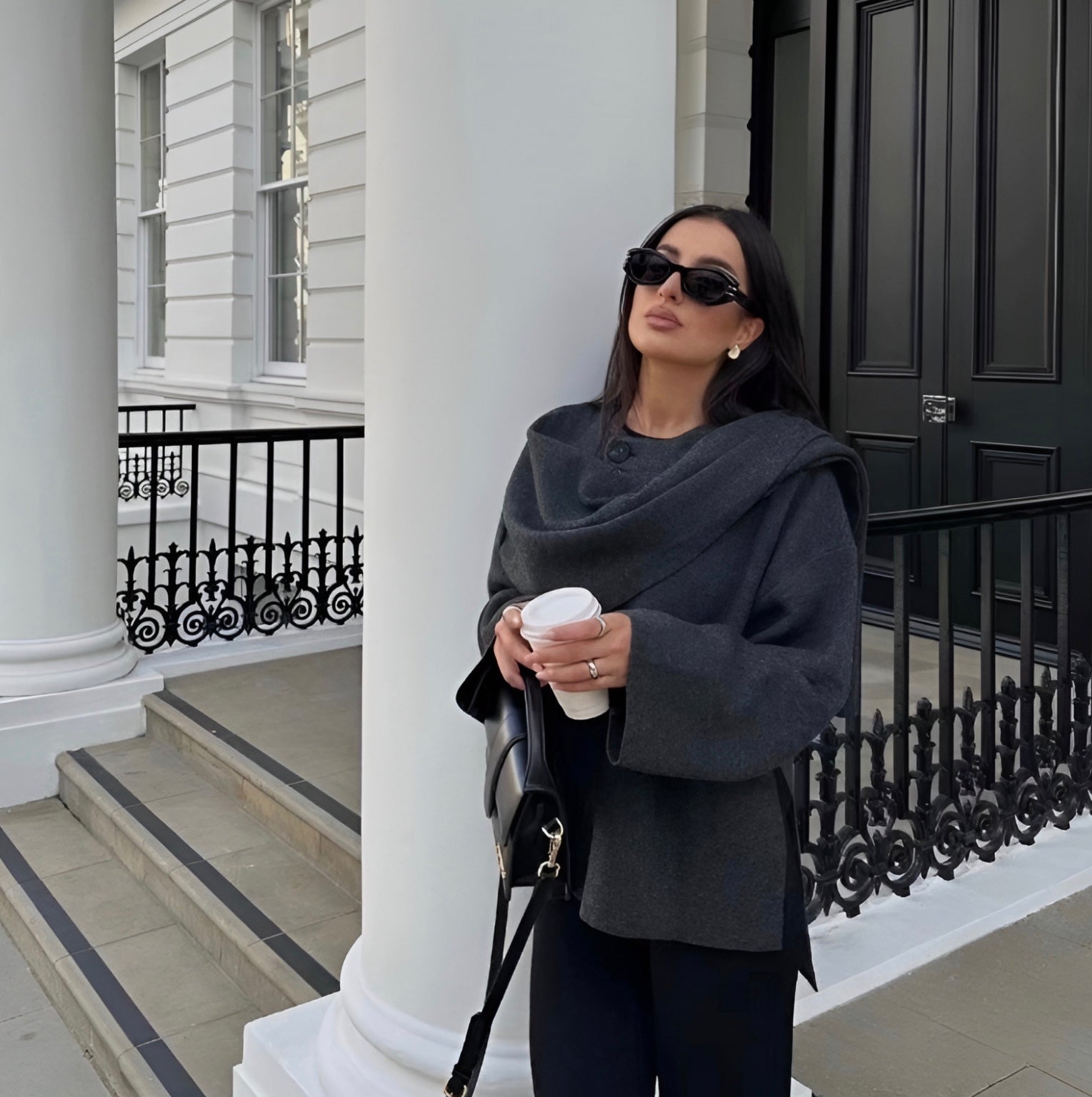 Stijlvolle en tijdloze Kallista jas in donkergrijs, perfect voor een chique, casual look. Gecombineerd met een tas en accessoires voor een verfijnde uitstraling.
