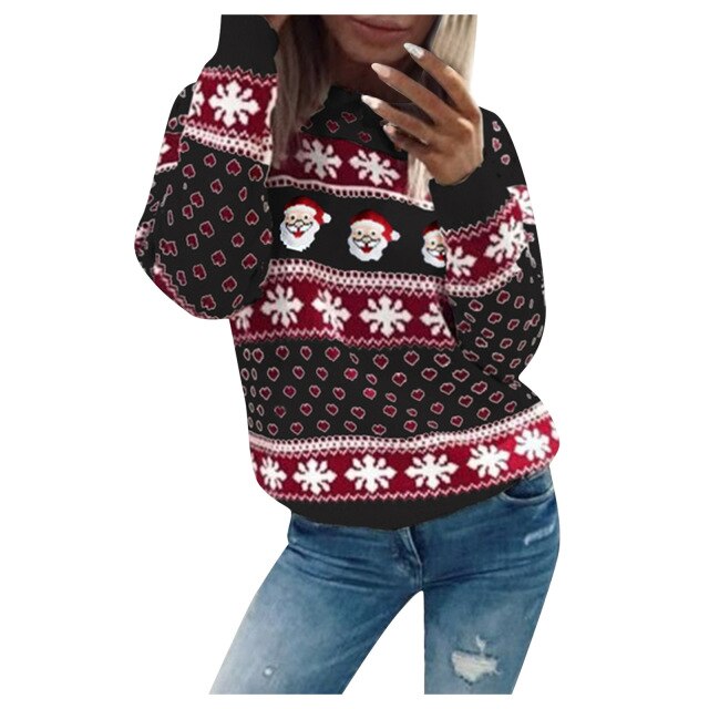 Model draagt een Kardora casual trui met een feestelijk kerstdesign. De trui heeft een patroon van kerstmannen, sneeuwvlokken en hartjes in rood, wit en zwart. Perfect voor de feestdagen met een comfortabele pasvorm. Gecombineerd met een spijkerbroek voor een speelse en gezellige look.