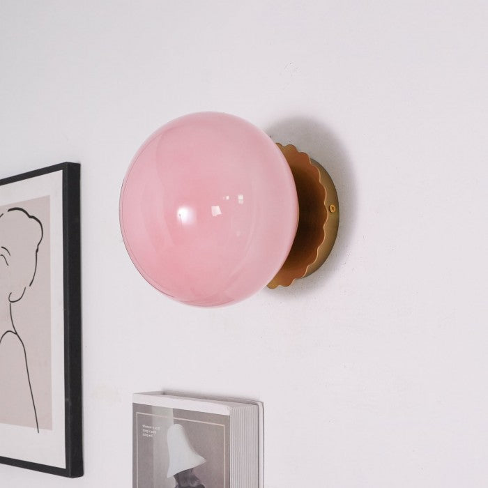 Lira hanglamp met een zachte roze glazen bol en een gouden wandbevestiging. De lamp straalt een warm en diffuus licht uit, waardoor een gezellige en stijlvolle sfeer ontstaat. Perfect als accentverlichting in woonkamers, gangen of slaapkamers.