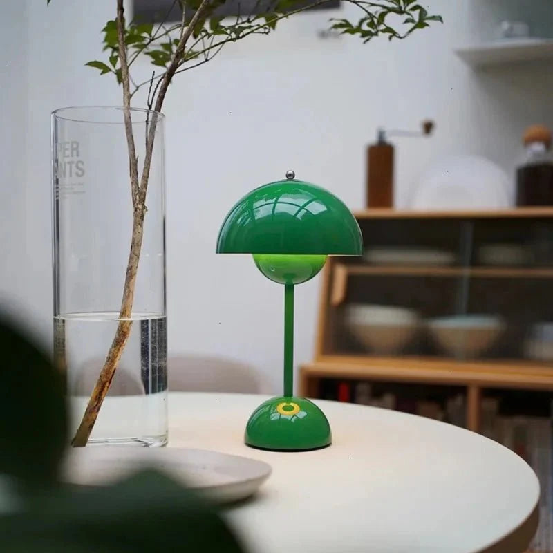 Een speelse LumiNova tafellamp in groen, met een unieke bloemvormige basis, geplaatst op een moderne ronde tafel. De lamp straalt een zachte, warme gloed uit en voegt een frisse, stijlvolle uitstraling toe aan elke ruimte, ideaal voor een sfeervolle inrichting.