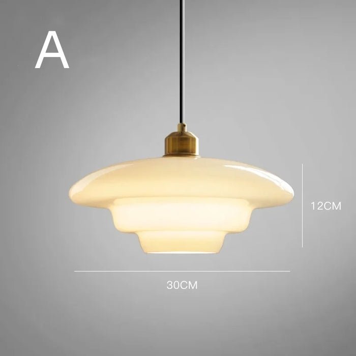  A single elegant white glass pendant lamp with a smooth layered design, suspended from a black cord. The lamp features a brass fixture at the top, adding a touch of sophistication. It measures 30cm in diameter and 12cm in height, perfect for creating a stylish and modern atmosphere in any room. The soft glow of the lamp complements the minimalistic aesthetic.