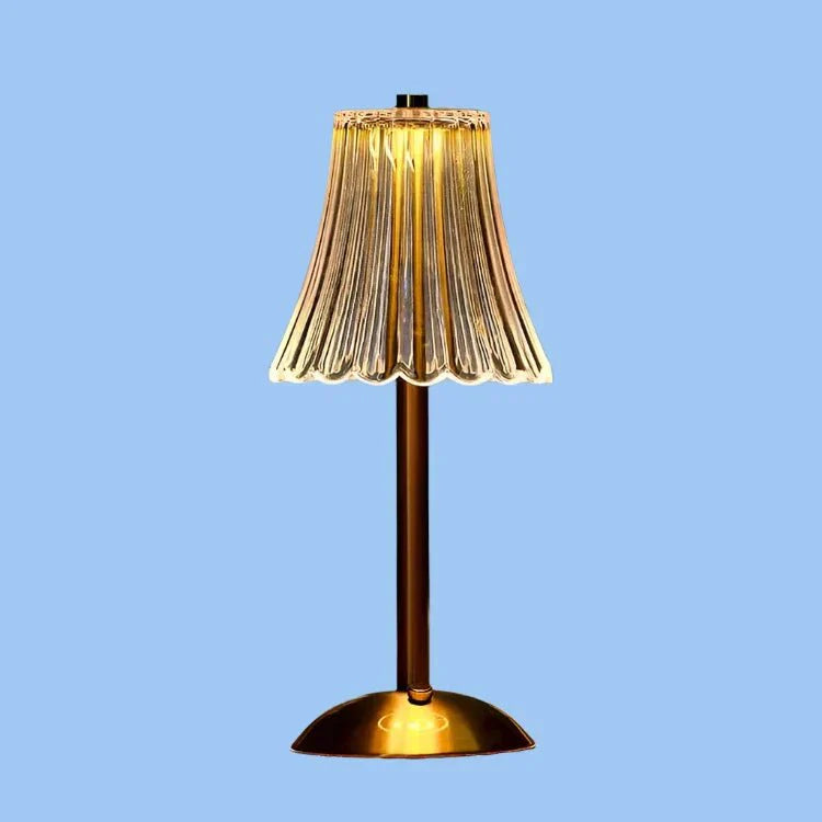 Een stijlvolle draadloze tafellamp met een gouden voet en een prachtig geplooide glazen lampenkap die warm gloeit, waardoor een elegante en moderne sfeer in elke kamer ontstaat.