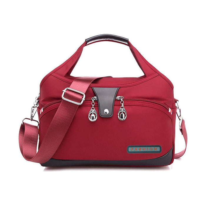 Stijlvolle rode handtas met schouderband, dubbele ritssluitingen en zilverkleurige details. De tas heeft een praktisch ontwerp met meerdere vakken en een afneembare, verstelbare schouderriem. Perfect voor dagelijks gebruik of zakelijke gelegenheden.