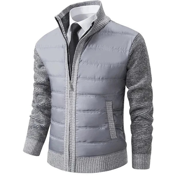 Lichtgrijs wintervest met gewatteerde panelen aan de voorkant en gebreide mouwen en zijkanten. Dit comfortabele en stijlvolle vest heeft een rits en is ideaal voor de koudere maanden. Perfect voor een moderne, casual look die zowel warmte als elegantie biedt.