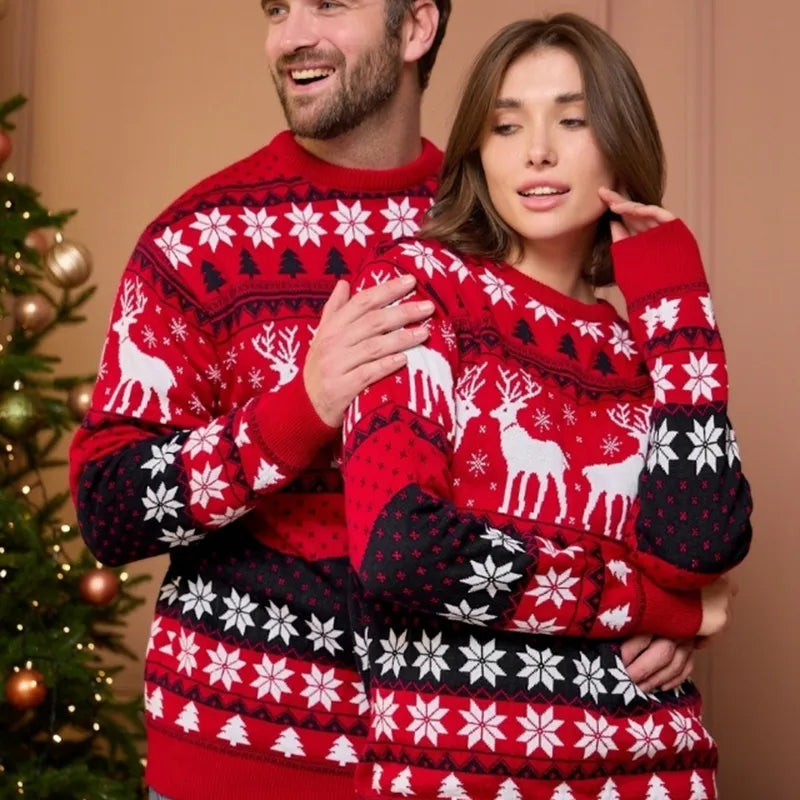 Een man en een vrouw dragen bijpassende kersttruien in rode en zwarte kleuren met een feestelijke print van rendieren, sneeuwvlokken en kerstbomen. De truien zijn stijlvol en comfortabel, ideaal voor de feestdagen.
