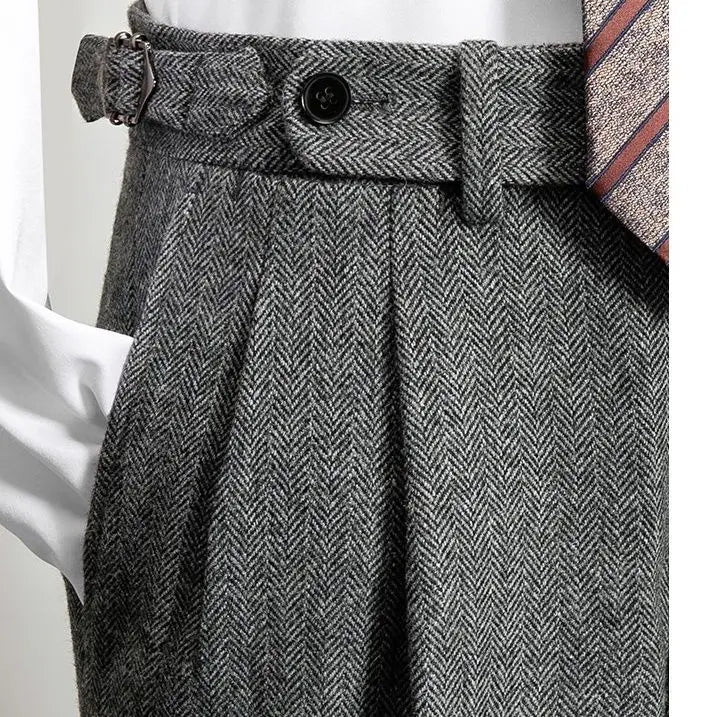 Detail van een groene, gemêleerde broek met een klassieke visgraatprint. De broek heeft een hoge taille met een riem en strakke plooien voor een elegante uitstraling. Perfect voor een veelzijdige, stijlvolle look die zowel casual als formeel kan worden gedragen.