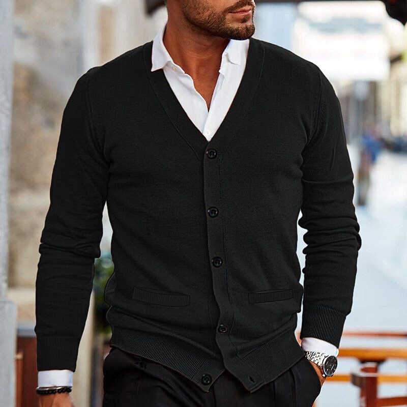 Man in een zwart casual vest met V-hals en knopen, gecombineerd met een witte overhemd, loopt door de stad. Het vest biedt zowel stijl als comfort, ideaal voor een casual, veelzijdige look.