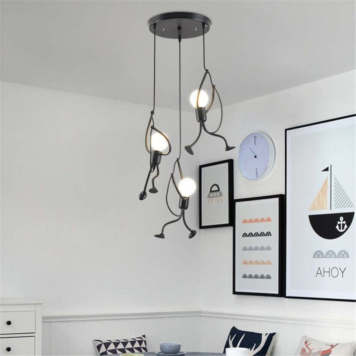 Een unieke, speelse industriële hanglamp bestaande uit drie figuren die een gloeilamp vasthouden, ideaal voor een modern interieur met een humoristische uitstraling