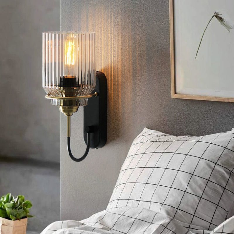 Deze wandlamp met een elegant geribbeld glazen scherm en een stijlvolle gouden afwerking biedt een perfecte combinatie van retro charme en moderne flair. De lamp verspreidt een zachte, warme gloed, waardoor het een ideale keuze is voor je slaapkamer of woonkamer, voor een gezellige en uitnodigende sfeer.