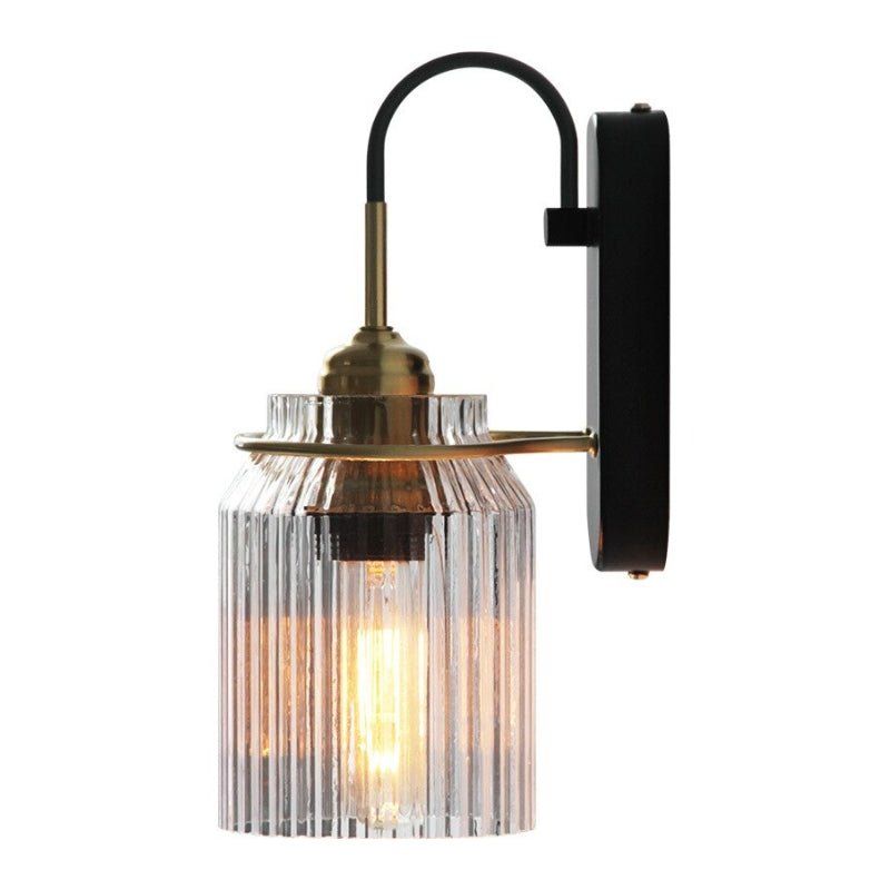 Deze wandlamp met een prachtig geribbeld glazen scherm en een combinatie van gouden en zwarte accenten brengt een klassieke, vintage charme in je interieur. Het warme licht dat door het glas schijnt, creëert een gezellige en uitnodigende sfeer. Perfect voor de woonkamer, slaapkamer of hal, voegt het een tijdloze stijl toe aan elke ruimte.