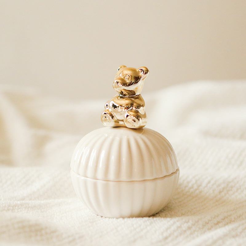 Een elegante opbergpot in de vorm van een schelp, met een schattige gouden beer als deksel. Het verfijnde ontwerp van de beer voegt een speelse en charmante uitstraling toe aan de pot, perfect voor het opbergen van kleine spullen met een vleugje elegantie.