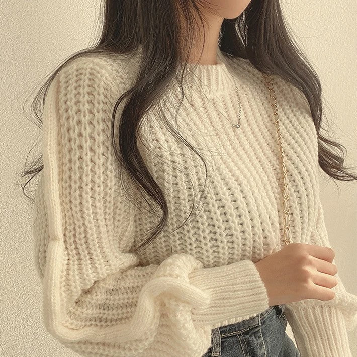 Model draagt een elegante witte gebreide trui van het merk Yvano. De trui heeft een comfortabele pasvorm met grove knit structuur en lange mouwen. Perfect te combineren met een high-waisted jeans of rok voor een casual en stijlvolle look. De trui straalt warmte en zachtheid uit, ideaal voor koude dagen.