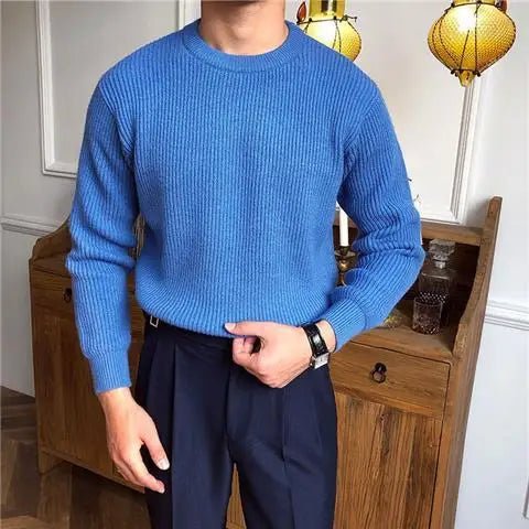 Man draagt een stijlvolle, comfortabele blauwe Zarvo Trui met ribstructuur en een ronde hals. Perfect gecombineerd met een donkere pantalon voor een nette en moderne uitstraling.