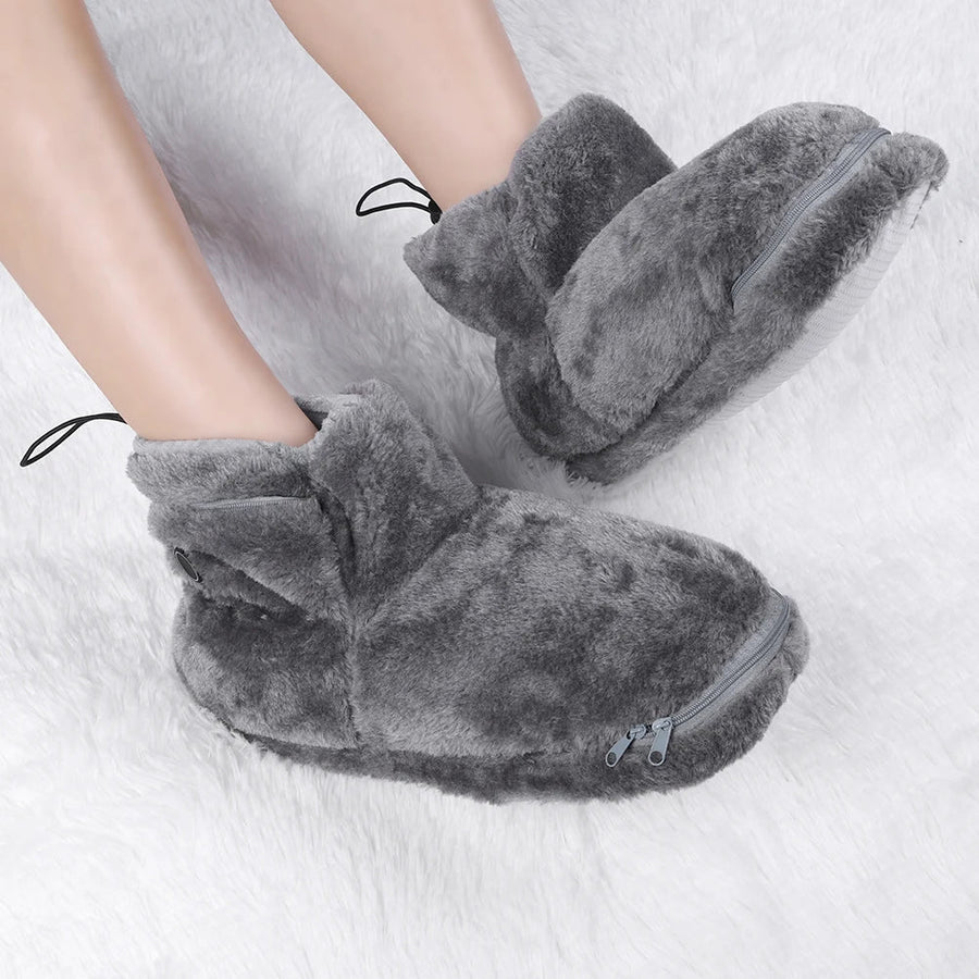 Zennor zip schoenen in grijs, gedragen op een witte zachte ondergrond. De schoenen zijn gevoerd met pluche stof, voorzien van een ritssluiting aan de voorkant en een verstelbare trekkoordsluiting aan de bovenkant. Perfect voor warme en comfortabele voeten in huis.