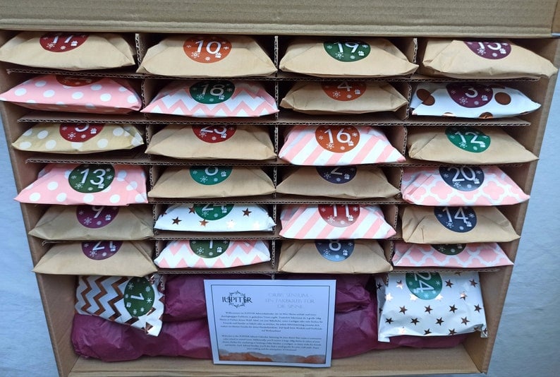 Een adventskalender met 24 kleurrijk verpakte zakjes, elk voorzien van een nummer en een vrolijk patroon. De kalender biedt een dagelijkse verrassing en is perfect voor de feestdagen, ideaal voor het creëren van een magische sfeer. Het ontwerp bevat zakjes met verschillende kleuren en stijlen, waaronder stippen, sterren en chevron patronen, die de kalender een speelse en betoverende uitstraling geven.