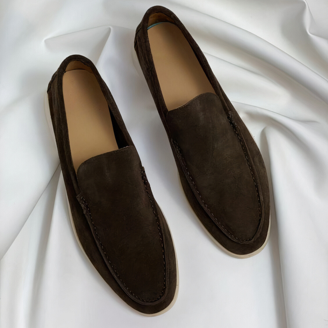 De afbeelding toont een paar Zodara klassieke herenloafers in een warme, donkerbruine kleur. Deze loafers hebben een luxueus, tijdloos ontwerp met een slanke en verfijnde uitstraling. De leren afwerking en de soepele zolen zorgen voor zowel comfort als stijl, waardoor ze geschikt zijn voor elke gelegenheid, van formeel tot casual. De minimalistische uitstraling maakt deze schoenen een perfecte keuze voor de modebewuste man die op zoek is naar tijdloze elegantie.