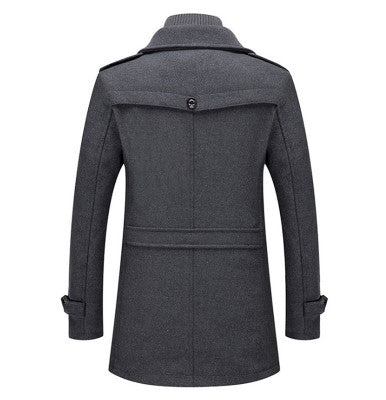 Het achteraanzicht van een luxe winterjas in grijs, met een klassieke kraag en een stijlvolle, goed gestructureerde pasvorm. De jas heeft een knoopsluiting bovenaan en een riem die de taille benadrukt, wat zorgt voor een verfijnde en moderne uitstraling. Perfect voor de winter, met een chique en elegante look.